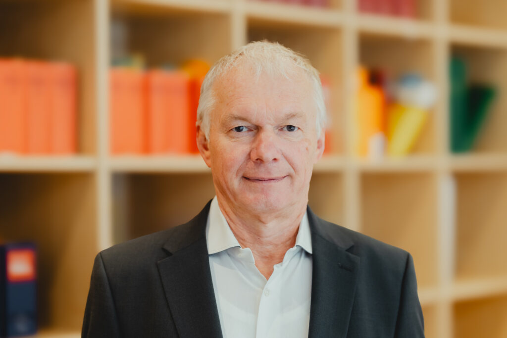 Jürgen Bellm lächelt vor einem Bücherregal