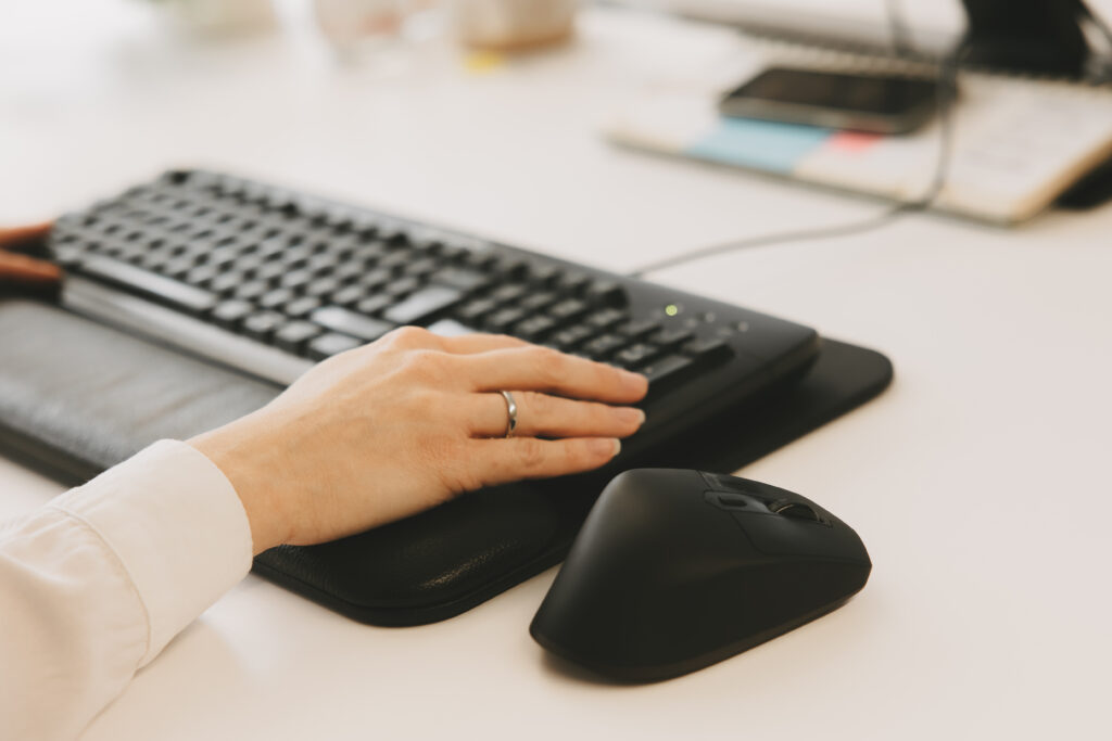 Hand tippt auf Tastatur mit Maus